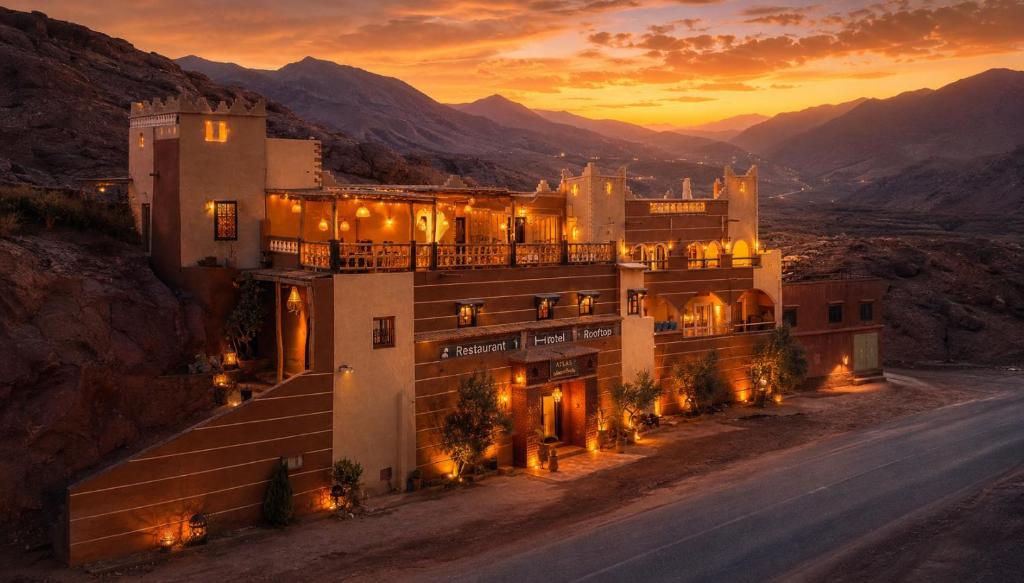 a building on a hill with a sunset in the background at Hotel Atlas Gorge Dades in Boumalne Dades