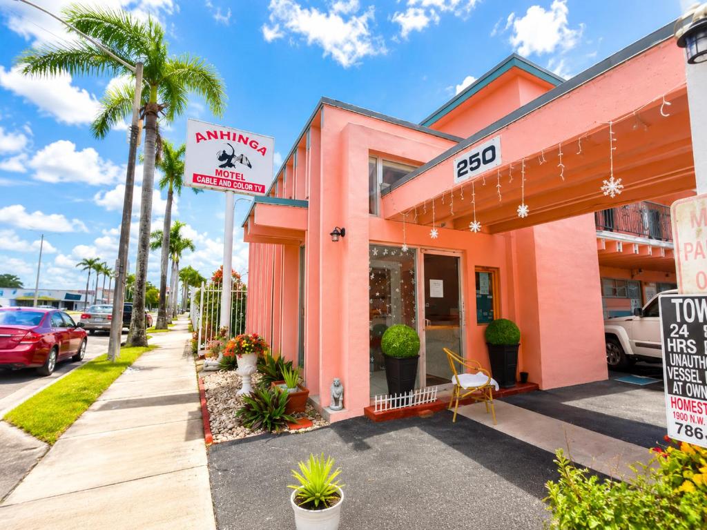 a pink building on a street with palm trees at Anhinga Motel Homestead FL in Homestead