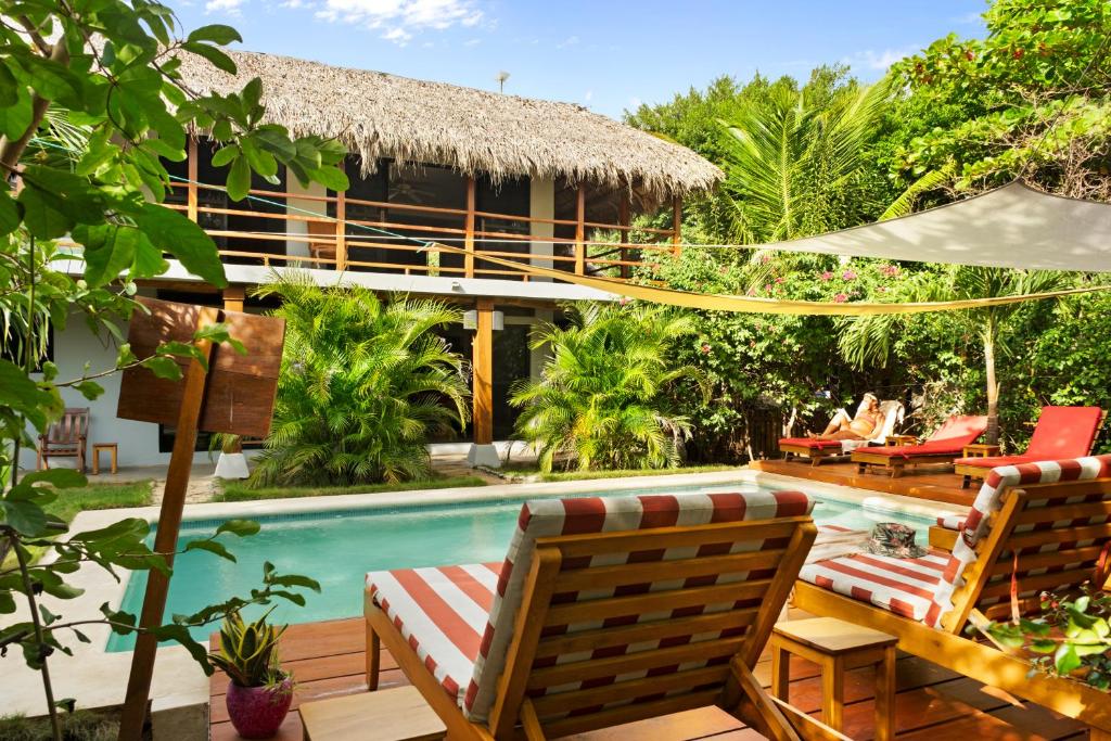 a resort with a pool and chairs and a house at Hotel Café Con Leche in Playa Santana