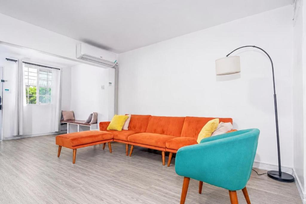 a living room with an orange couch and two chairs at Chill Haven in Kingston