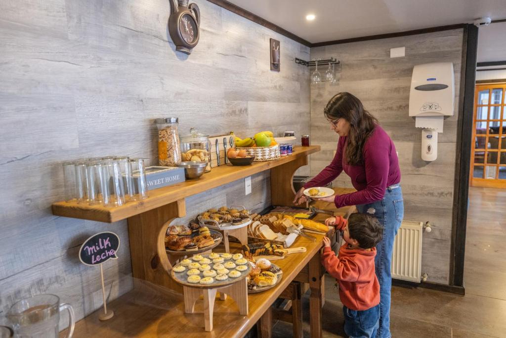a woman and a child standing at a table with food at Nikos II Adventure in Puerto Natales
