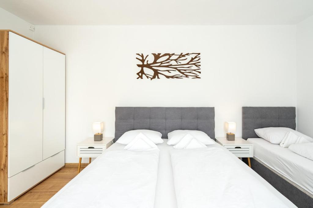 a white bedroom with two beds and a mirror at Apartmány Oravskie in Zuberec
