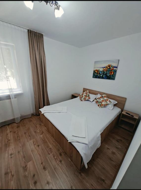 a bedroom with a bed with white sheets and wooden floors at Codruta Home in Râmnicu Vâlcea