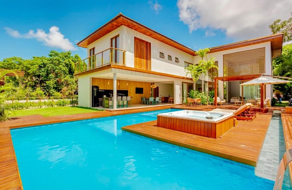 a villa with a swimming pool and a house at Green House Praia do Forte- 4 Suítes Premium in Mata de Sao Joao
