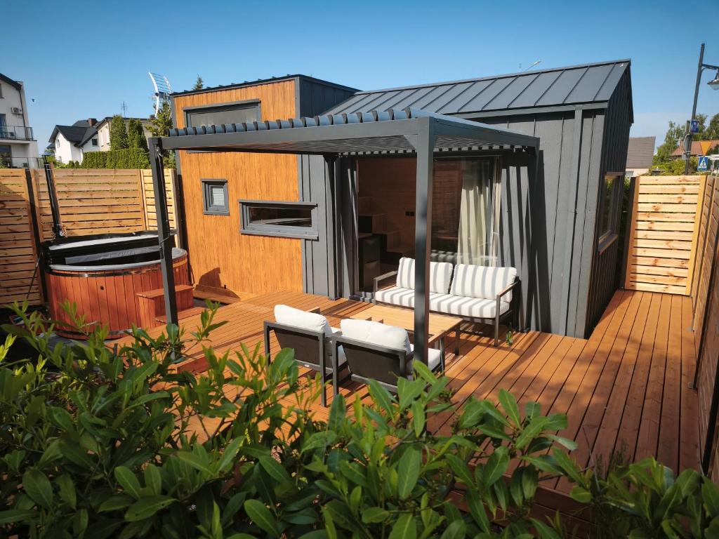 a deck with white chairs and a black roof at Tiny Vinkel - Domki Tiny House Jastarnia in Jastarnia