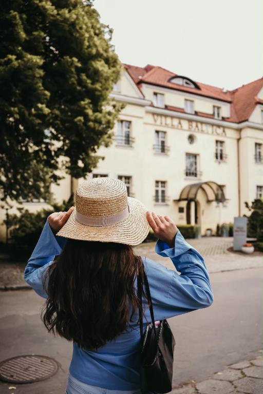 a woman wearing a straw hat in front of a building at Hotel Villa Baltica in Sopot
