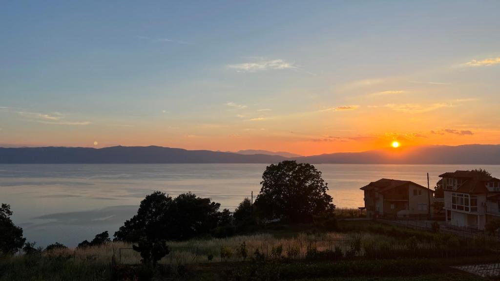 a sunset over the water with a house in the foreground at NINAS Apartments in Elshani