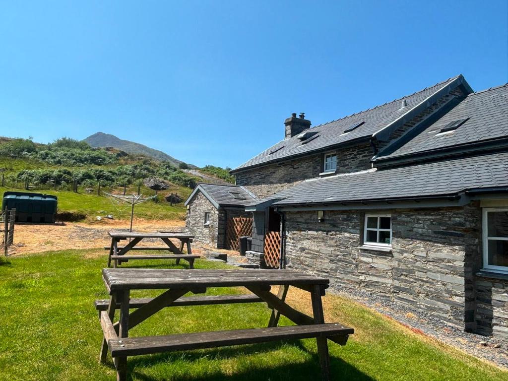 two picnic tables in front of a stone building at Ty Siabod in Betws-y-coed