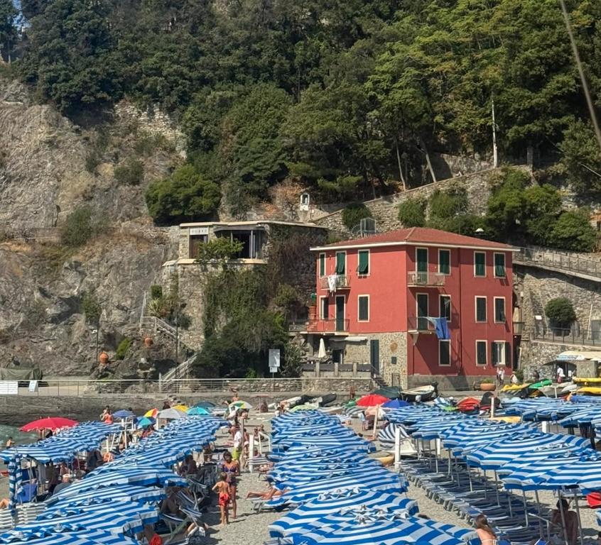 a bunch of blue chairs and umbrellas on a beach at Benvenuto Beach House in Monterosso al Mare