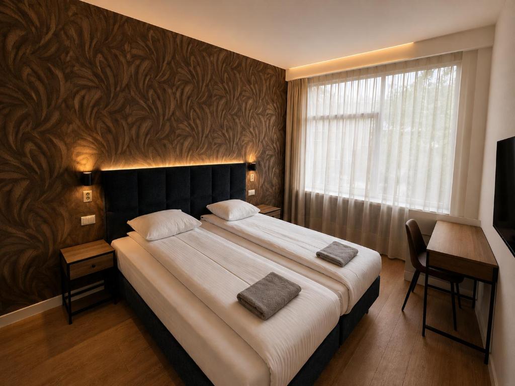 a bedroom with a large bed with a desk and a window at Hotel Holland Lodge in Utrecht