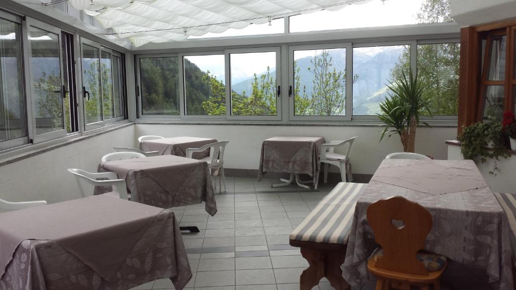 een restaurant met tafels en stoelen in een kamer met ramen bij Gasthof Gemse in Planol