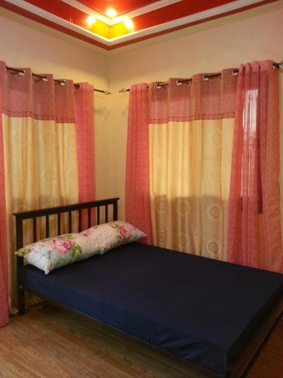 a bedroom with curtains and a bed with a pillow at Vhauschild Transient Rooms -B in Alaminos