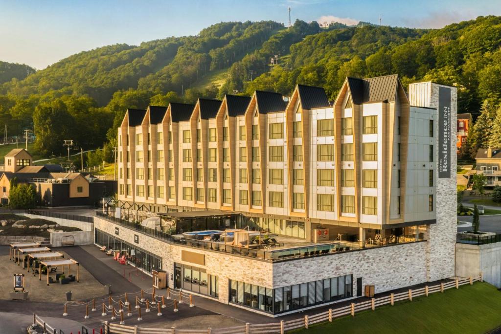 an aerial view of a hotel with mountains in the background at Residence Inn by Marriott Bromont in Bromont