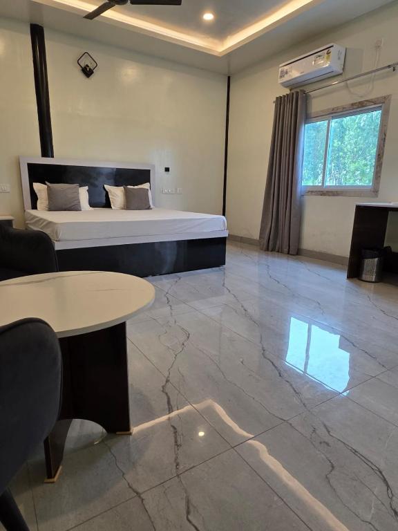 a large room with a bed and a table and a couch at Ganga Bliss Riverside in Haridwār