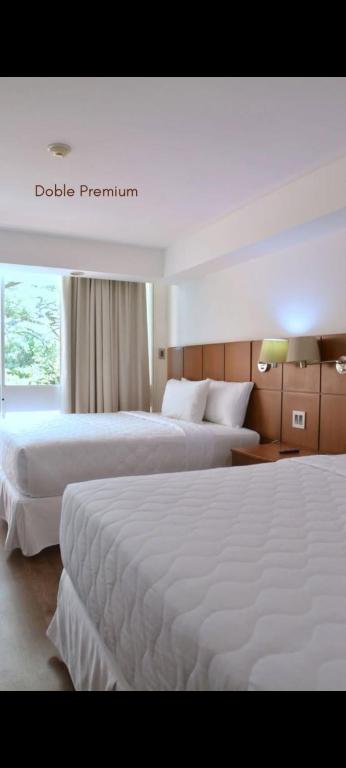 a hotel room with two beds and a window at Hotel Jirahara in Barquisimito