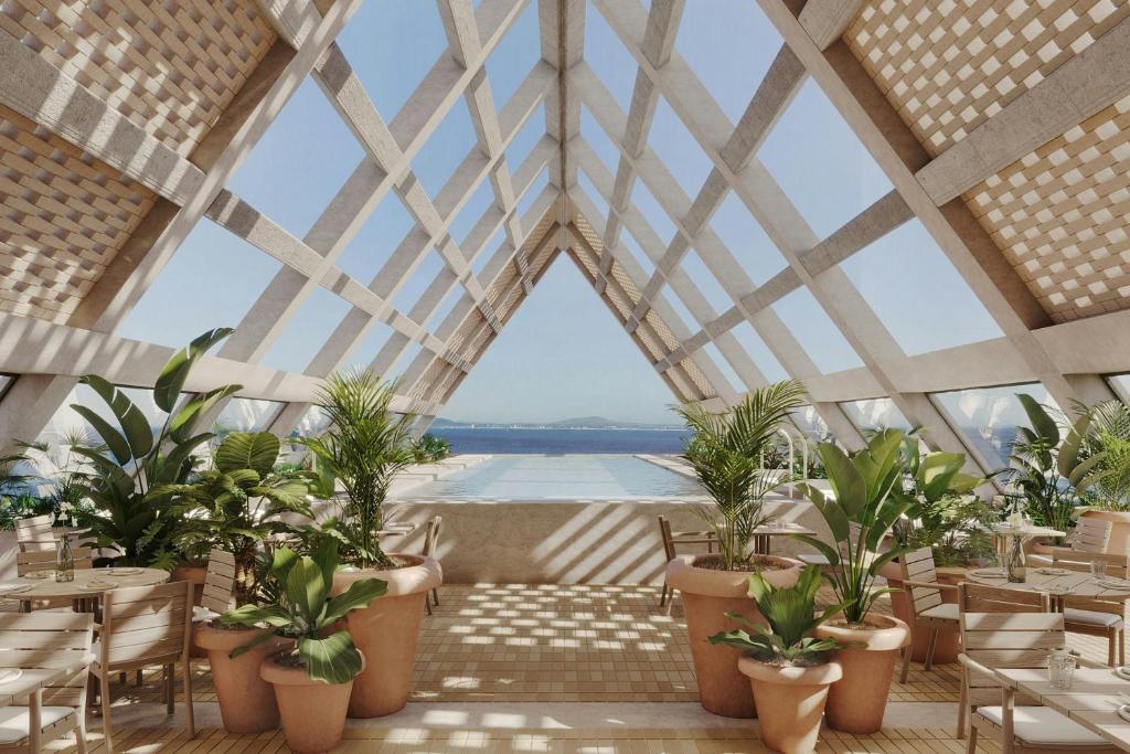 a restaurant with potted plants and a large window at The Cape Town EDITION in Cape Town