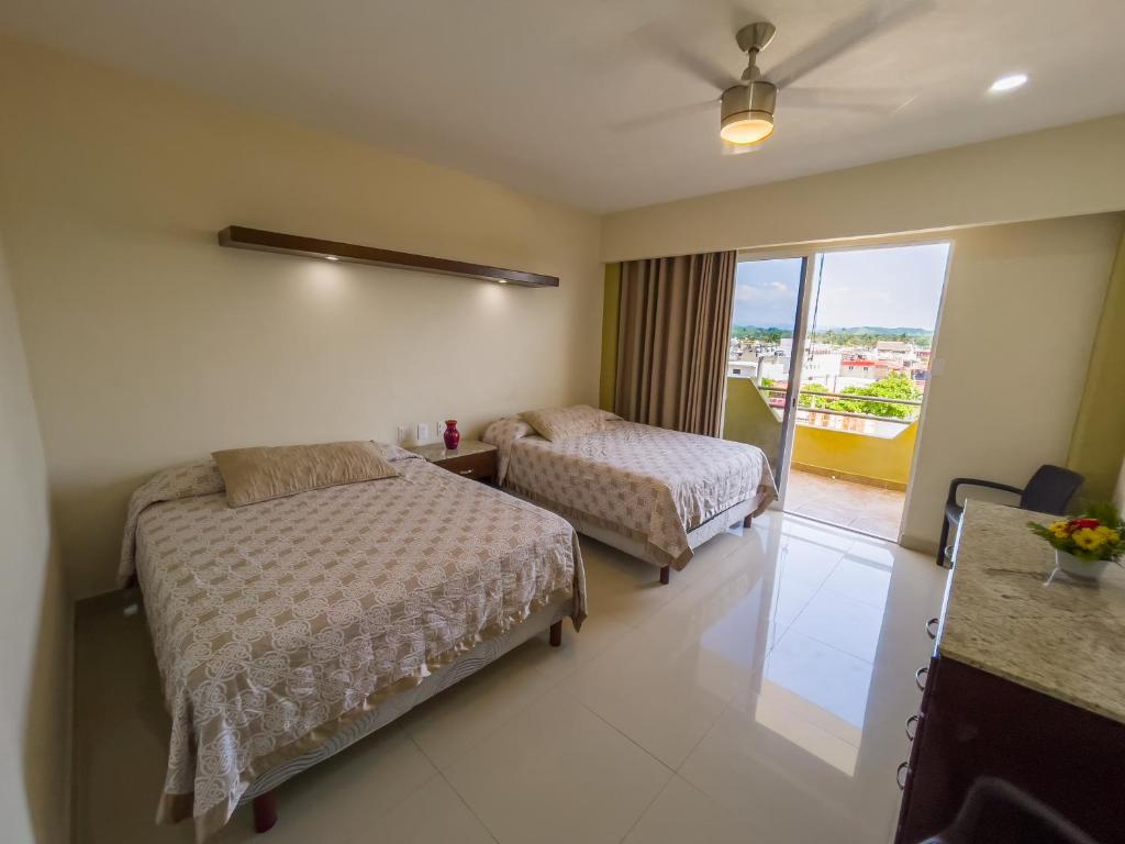a hotel room with two beds and a balcony at Hotel Bogavante in Barra de Navidad