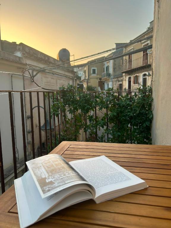 Ein offenes Buch liegt auf einem Holztisch auf einem Balkon in der Unterkunft Maltese16 in Modica