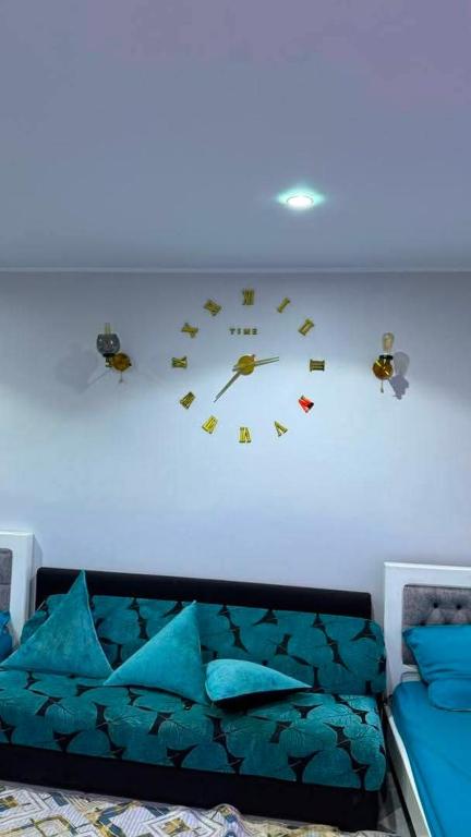 a clock on a wall above a bed with blue pillows at Salamandre in La Salamandre