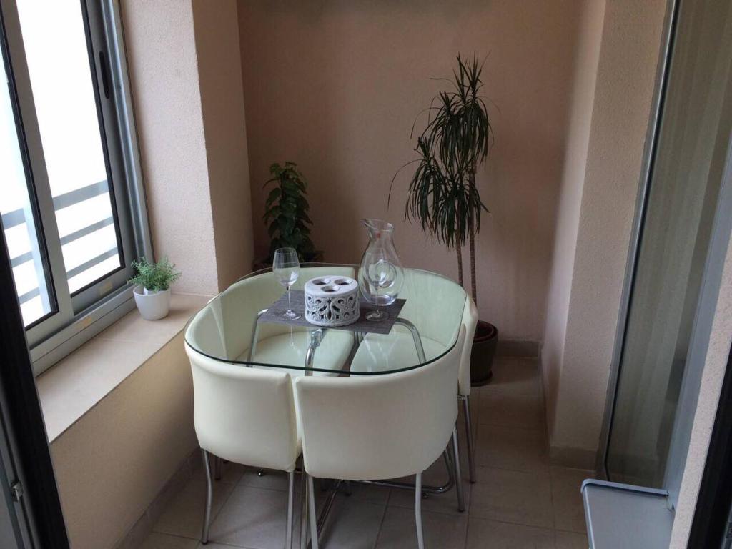 einen Glastisch in einem Zimmer mit Stühlen und einem Fenster in der Unterkunft Apartment Gorki in Belgrad