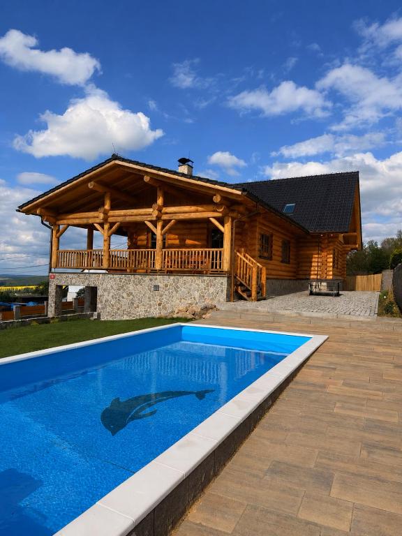 a log cabin with a swimming pool in front of a house at Srub Chodov in Chodov