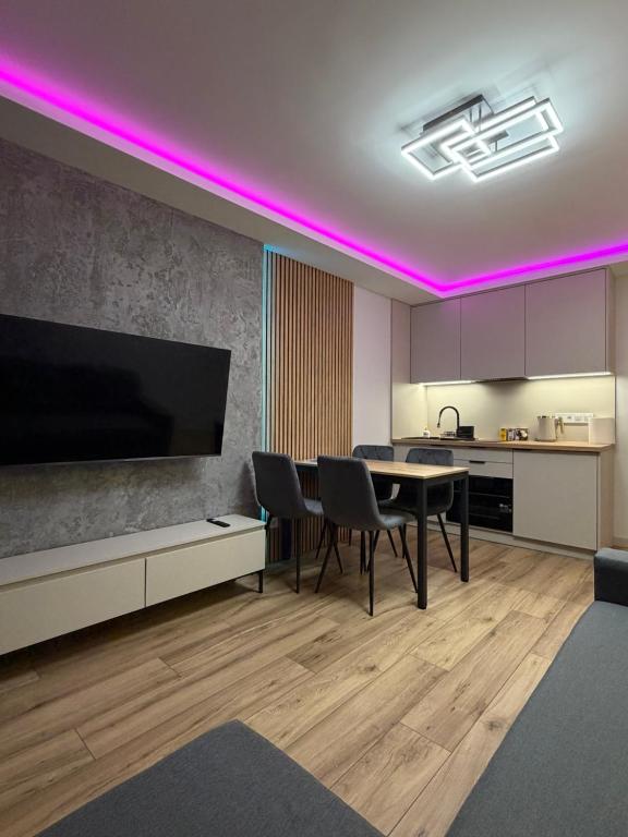 a kitchen and dining room with a table and purple lighting at MAX Apartaments in Częstochowa