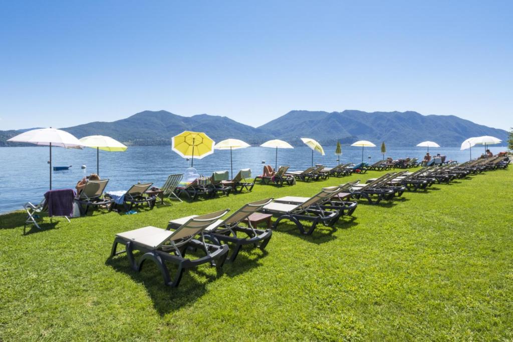 a row of lawn chairs and umbrellas on the beach at Studio 2- lake view in Oggebbio