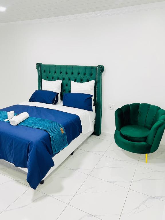 a bedroom with a bed and a green chair at Botha Villa Lodge Goodwood in Cape Town