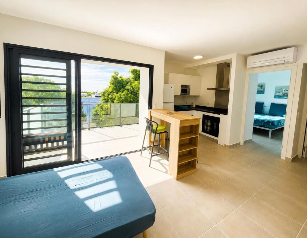 a bedroom with a bed and a kitchen with a balcony at Blue sunset - Appartement avec vue mer in Papeete