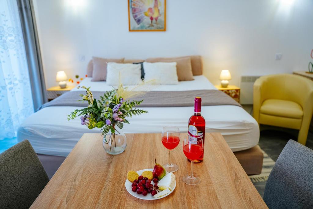 a table with a bottle of wine and a plate of fruit at Infinity Apartman in Esztergom