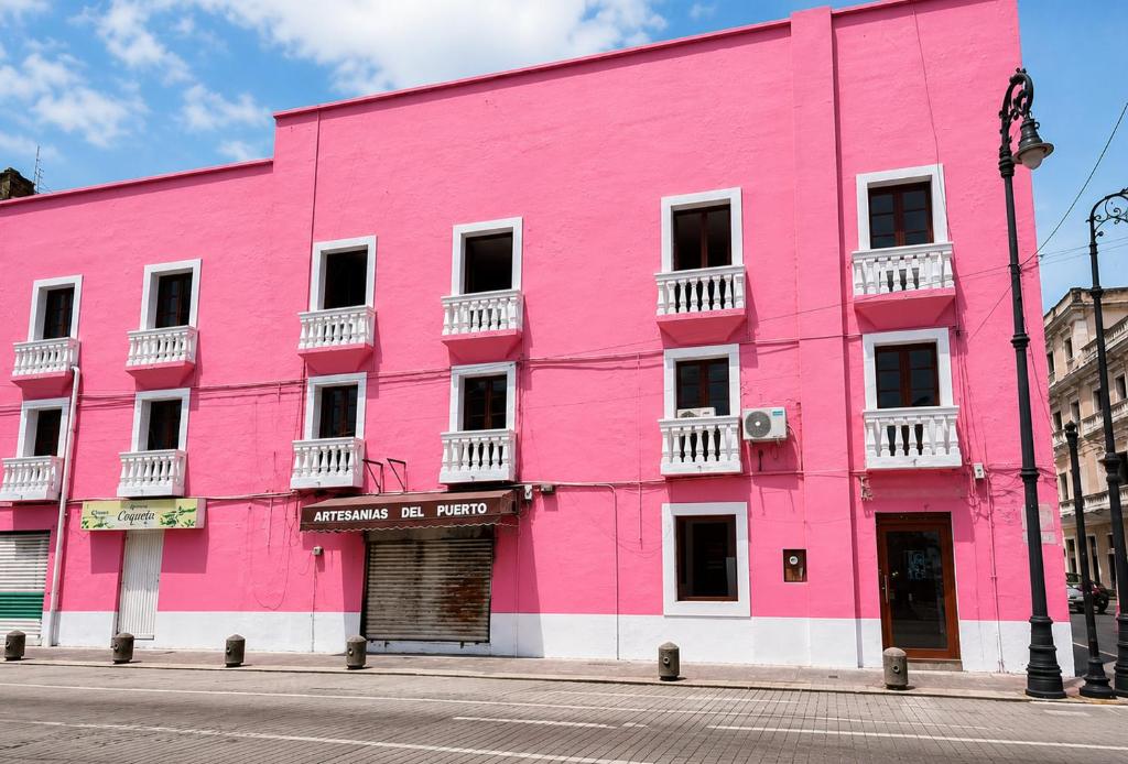 ein rosafarbenes Gebäude an einer Straßenseite in der Unterkunft Hotel Santander Veracruz in Veracruz