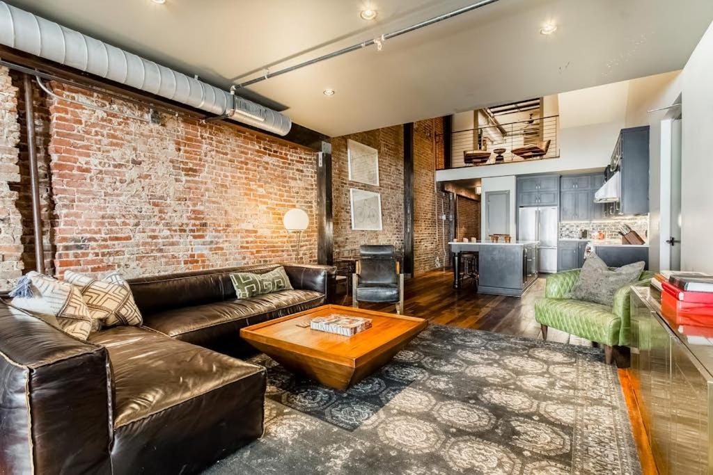 a living room with a couch and a brick wall at Tasteful Loft in Nashville