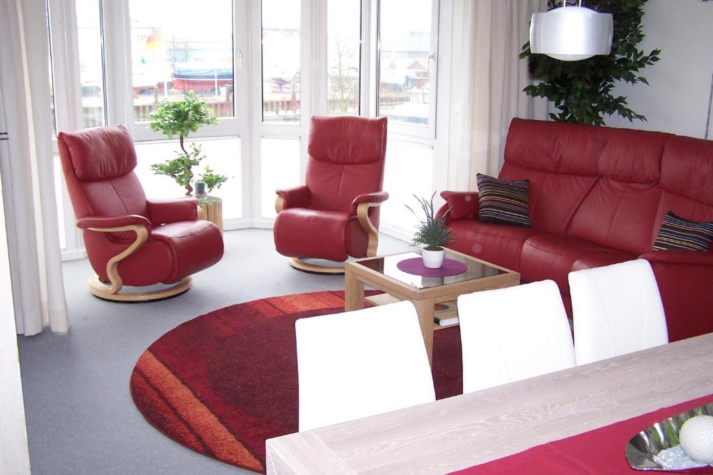 uma sala de estar com cadeiras vermelhas e um sofá vermelho em Marina 38-2 em Cuxhaven