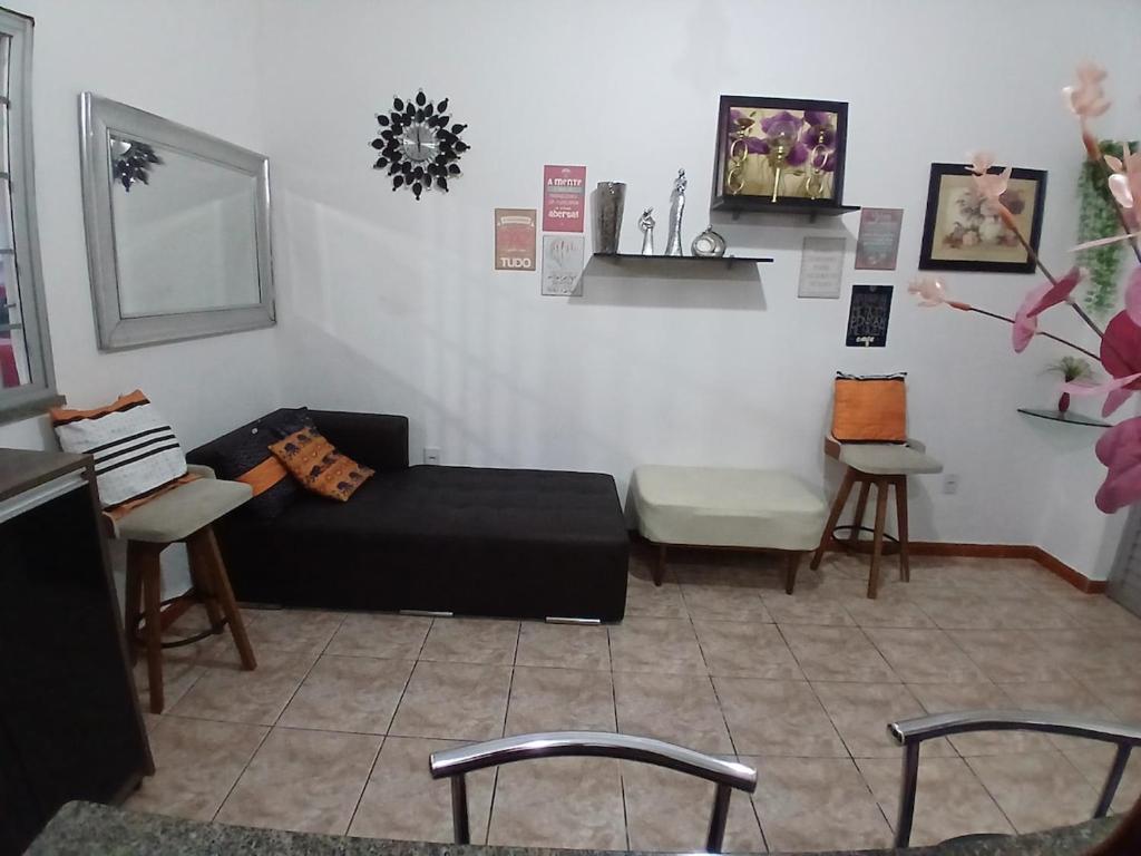 a living room with a black couch and two chairs at Casa aconchegante in Manaus