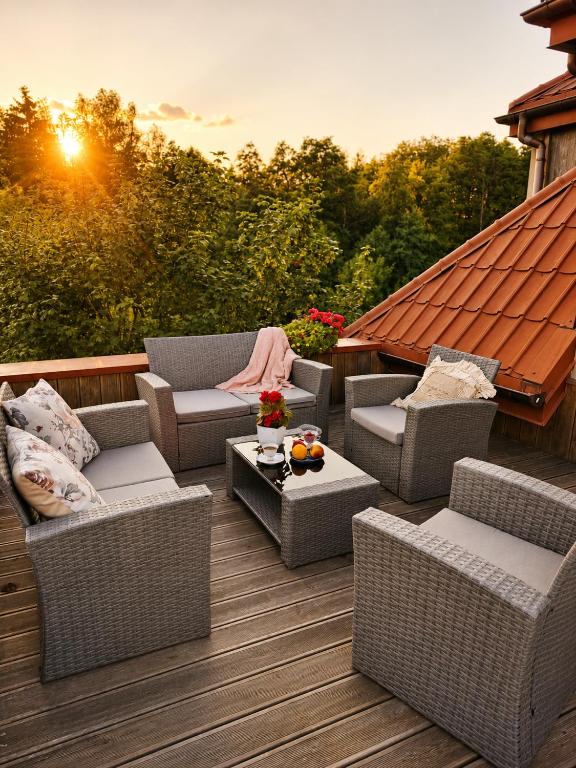 eine Terrasse mit Korbstühlen und -tischen und dem Sonnenuntergang in der Unterkunft Dom Noemi in Płock