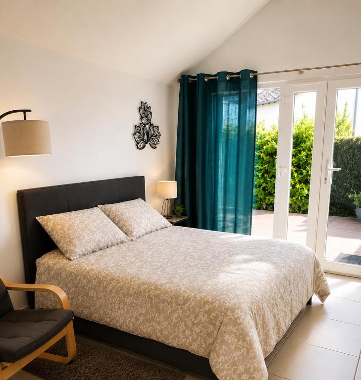 a bedroom with a bed and a chair and a window at Studio Terrasse - Parking gratuit in Orléans