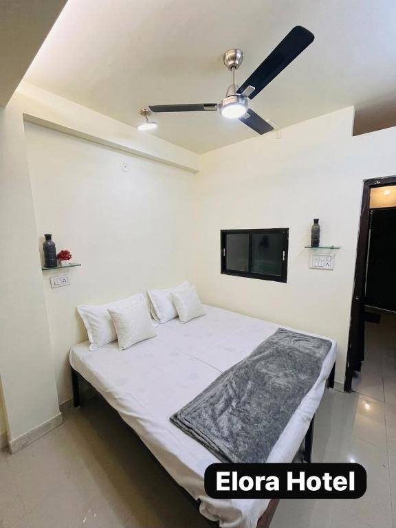 a bedroom with a bed with a tv on the wall at Elora Hotel in Ujjain