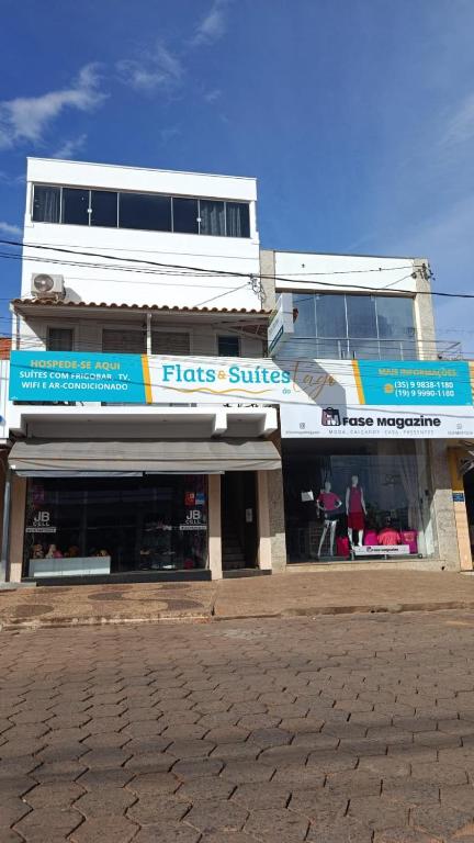 a store front of a building with blue signs at Flats & Suítes do Lago in Guapé