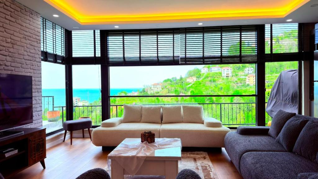 a living room with a couch and a large window at cam teraslı köyevi in Cayeli