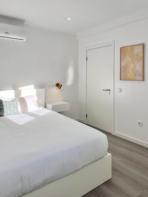 a white bedroom with a white bed and a door at Waves Madeira I in Caniçal