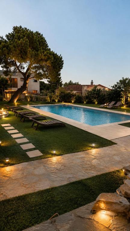 a large swimming pool with lights in the grass at Galini Hotel in Agia Marina Aegina