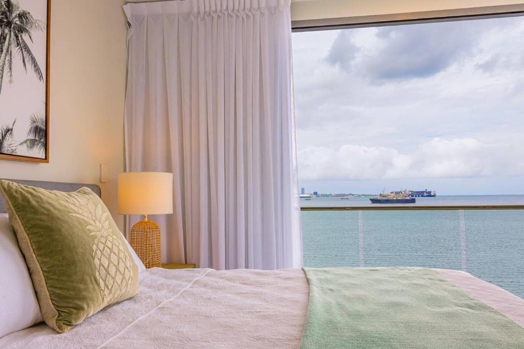 a bedroom with a large window with a view of the ocean at 403 - Suva City Views Oceanfront Large Balcony in Suva