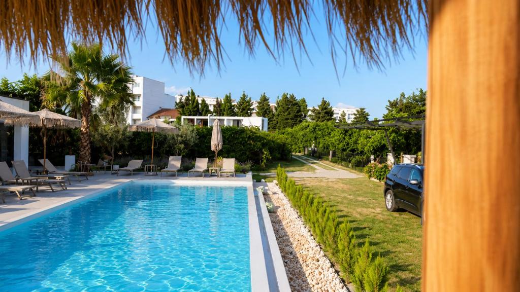 a swimming pool with a car parked next to a house at Apartaments Queen in Ulcinj