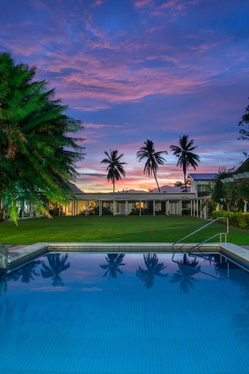 a large swimming pool in front of a house with palm trees at Fiji Gateway Hotel in Nadi