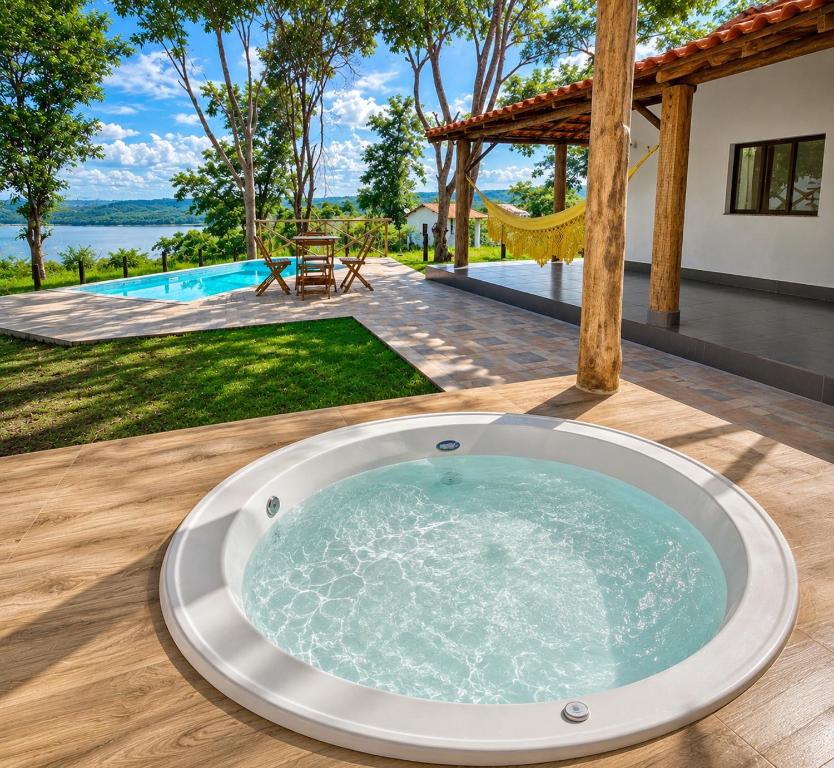 a jacuzzi tub on a deck with a view of a backyard at Casa com Jacuzzi Charme Corumbá in Alexânia