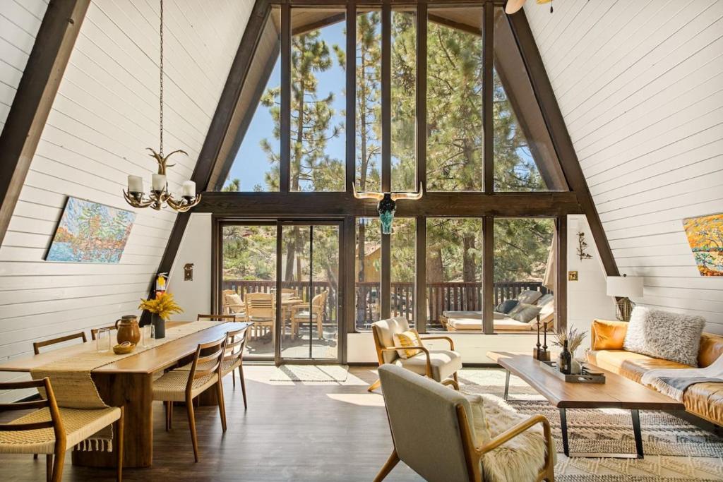 a living room with a large window and tables and chairs at Larks Nest in Big Bear Lake in Big Bear Lake