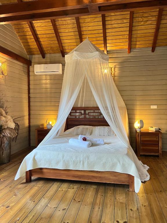 a bedroom with a bed with a mosquito net at Lodge Eden, SPA Privatif in Les Abymes