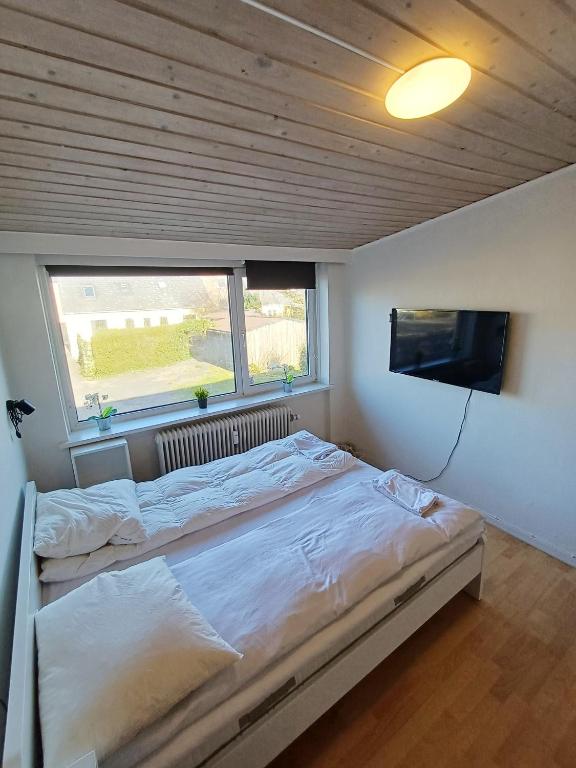 a bedroom with a large bed and a flat screen tv at Double room 5 with Free Parking in Nørresundby