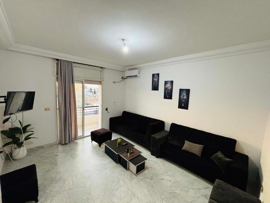 a living room with a black couch and a table at Le bienvenu in Sousse