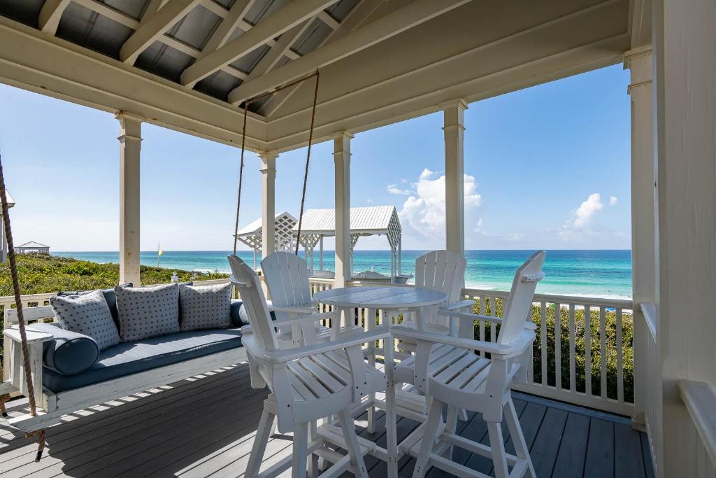 a porch with a table and chairs and the ocean at Magnolia Honeymoon Cottage in Santa Rosa Beach